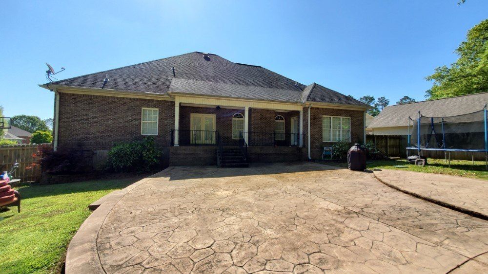 A large brick house with a trampoline in the backyard.