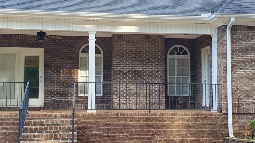 A brick house with a porch and a ceiling fan.