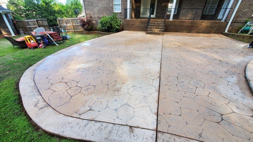 There is a concrete patio in the backyard of a house.