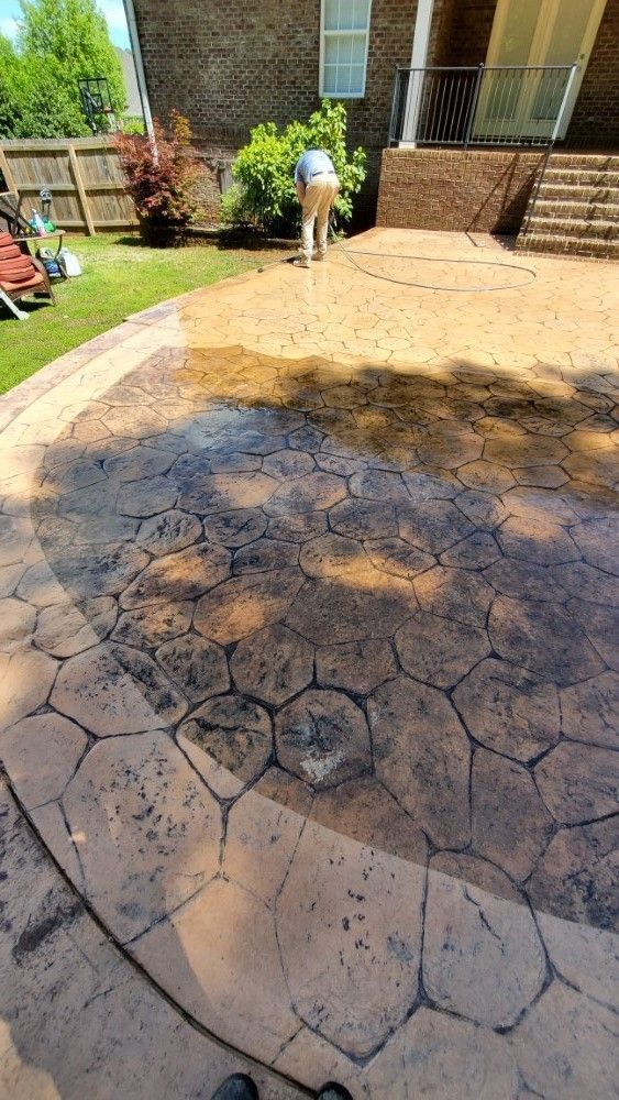 A person is standing on a concrete patio in front of a house.