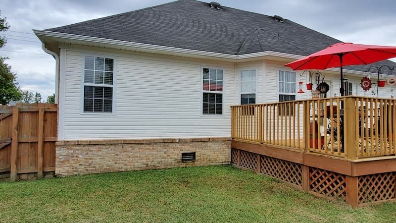 A white house with a wooden deck and a red umbrella.