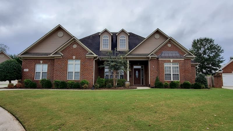 A large brick house with a lush green lawn in front of it