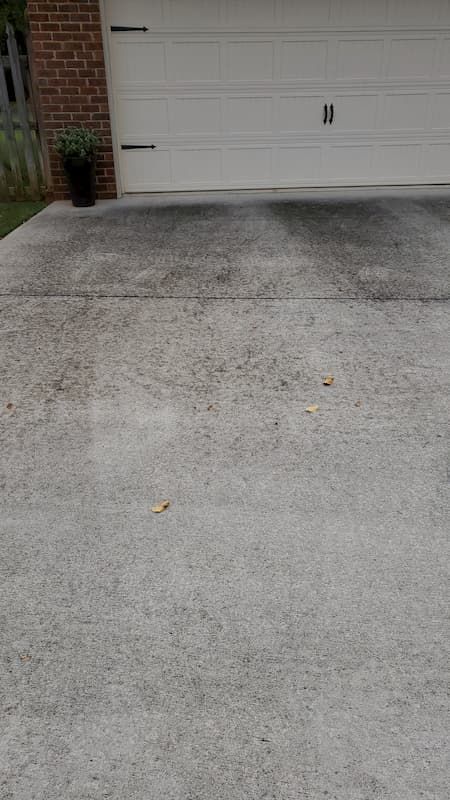 A concrete driveway with a garage door in the background.