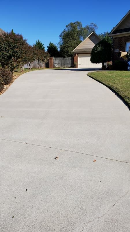 A concrete driveway leading to a house on a sunny day.