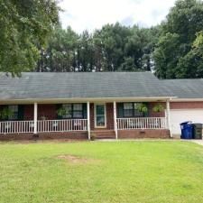 A brick house with a porch and a garage is for sale.