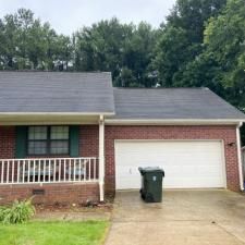 A brick house with a garage and a trash can in front of it.