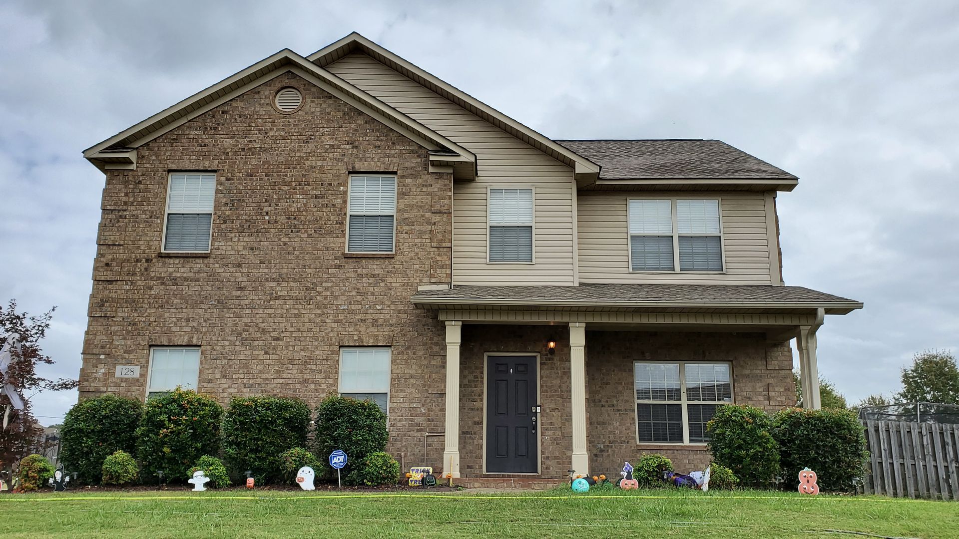 A large brick house with a large lawn in front of it.