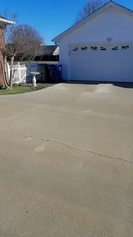 A driveway leading to a house with a white garage door.