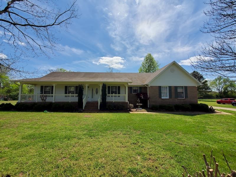 A brick house with a large lawn in front of it.