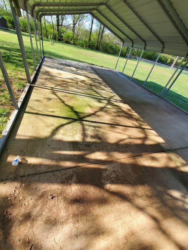 A covered walkway leading to a grassy field.