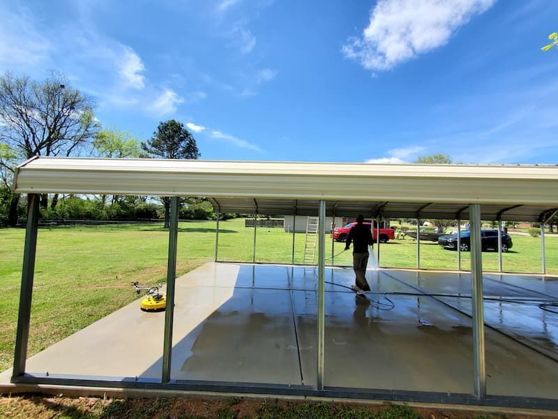 A man is washing a carport on a sunny day.