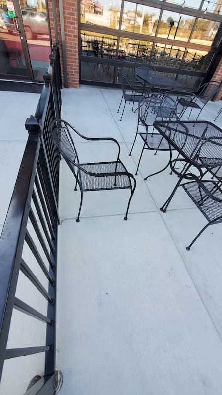 A balcony with tables and chairs and a railing.