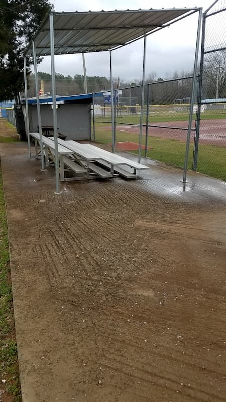 A baseball dugout with bleachers and a fence in the background.