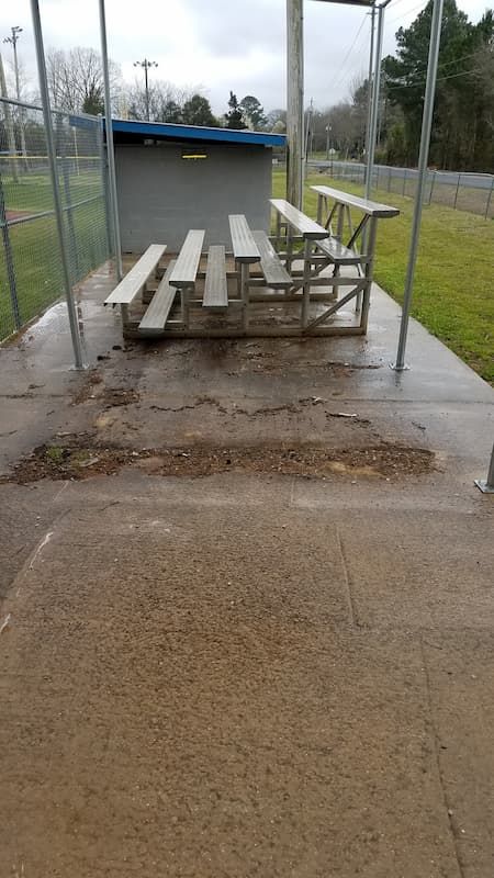 A picnic table is sitting on top of a concrete patio next to a fence.