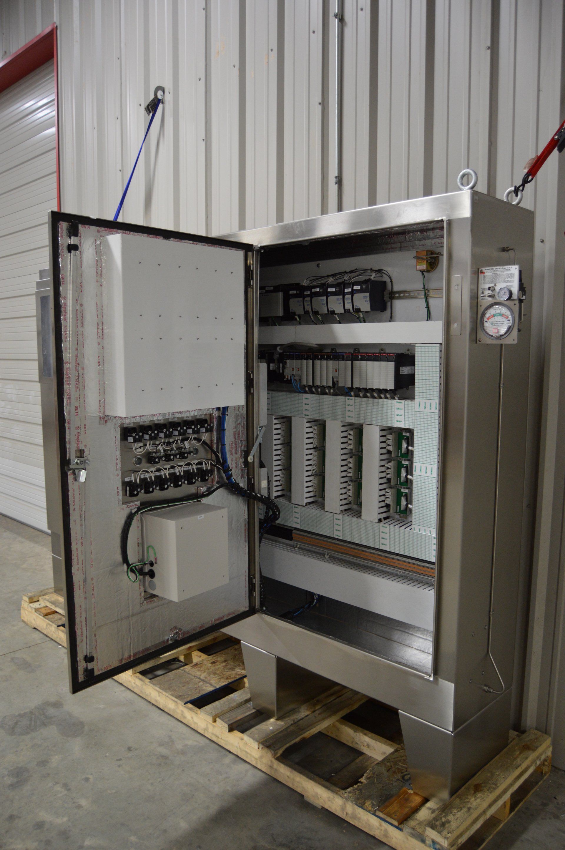 A stainless steel control panel is sitting on a wooden pallet.
