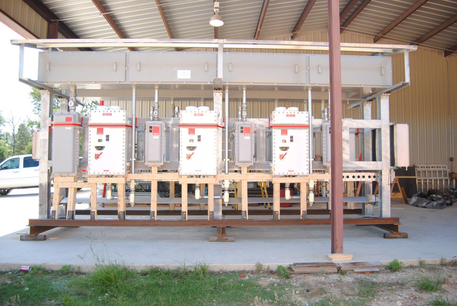 A row of electrical boxes are lined up under a roof