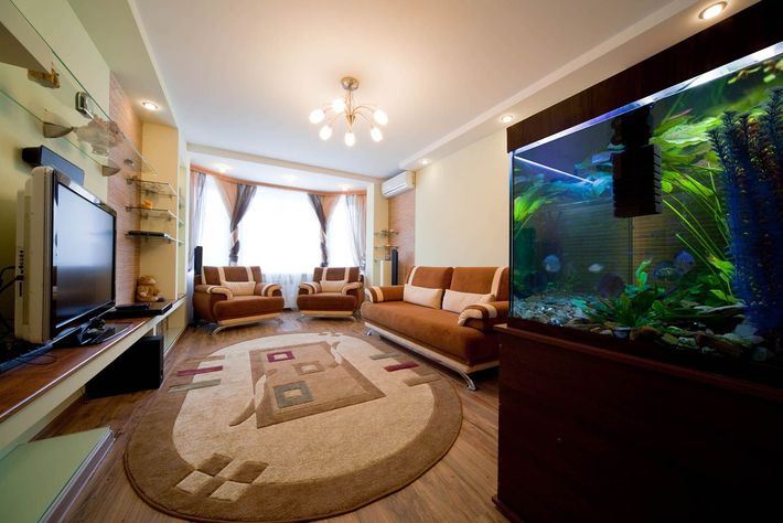 A living room with a couch , chairs , television and a fish tank.