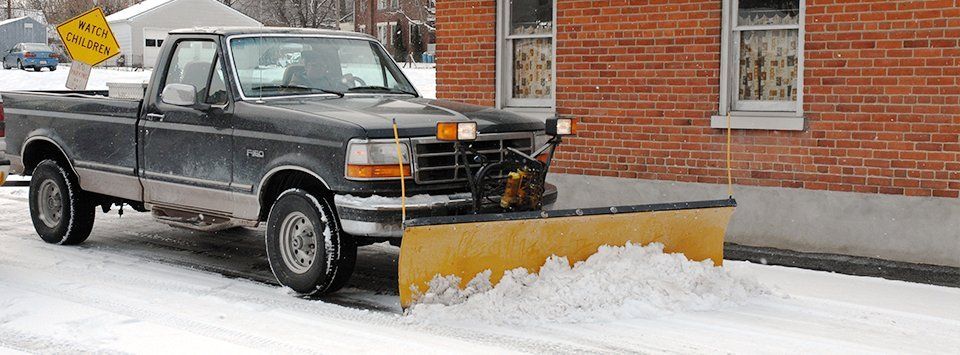 Black truck plowing snow on the road