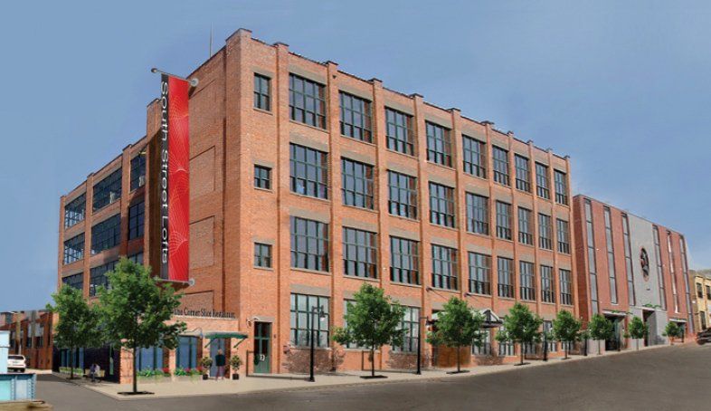 A large brick building with lots of windows and trees in front of it.