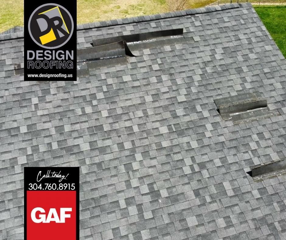 Gray shingled roof with two skylights and roofing company logos in the corner