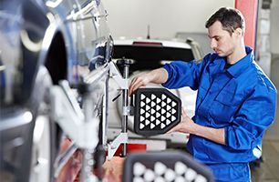 A man in a blue uniform is working on a car in a garage