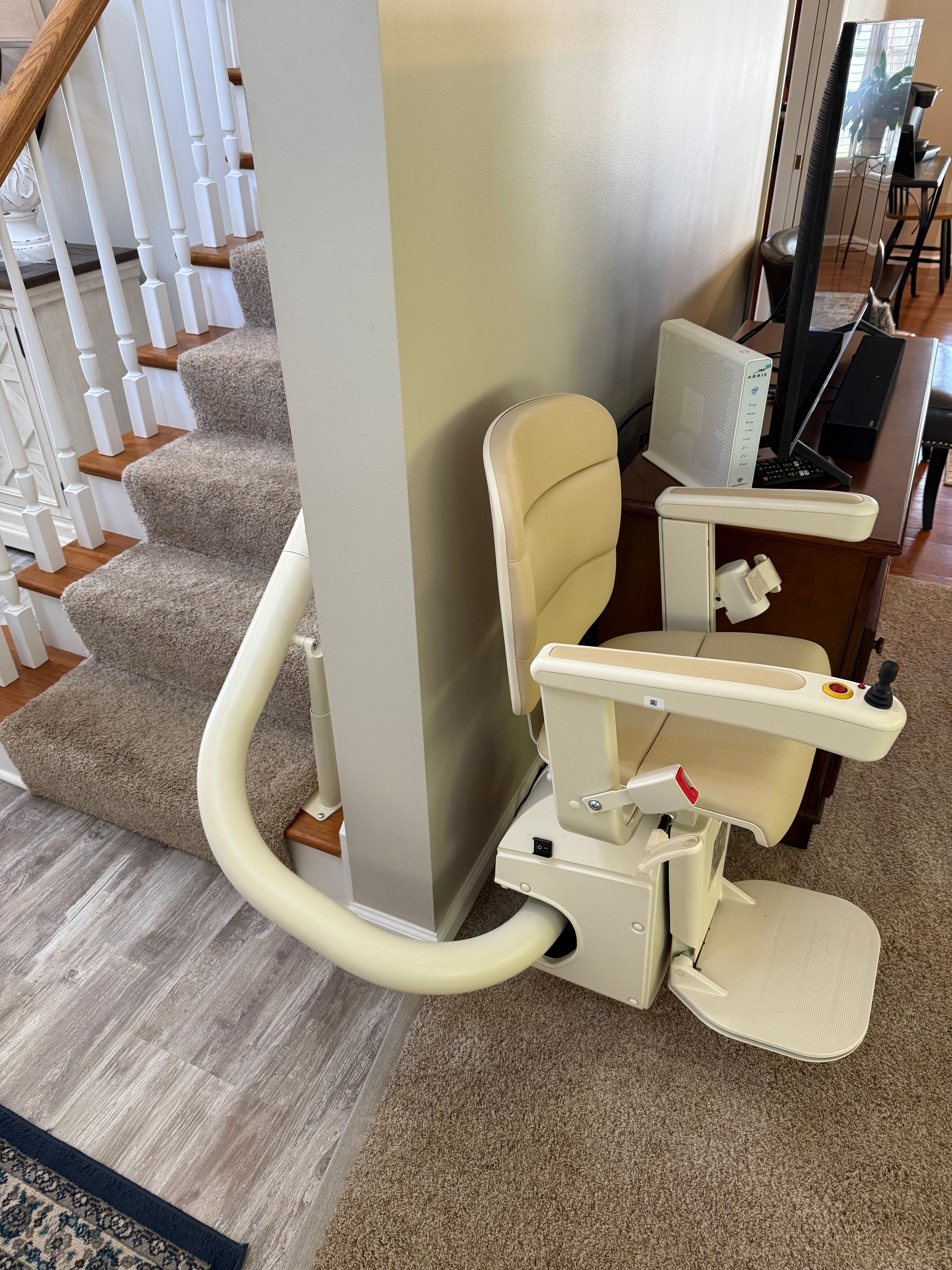 A white stair lift is sitting next to a staircase in a living room.