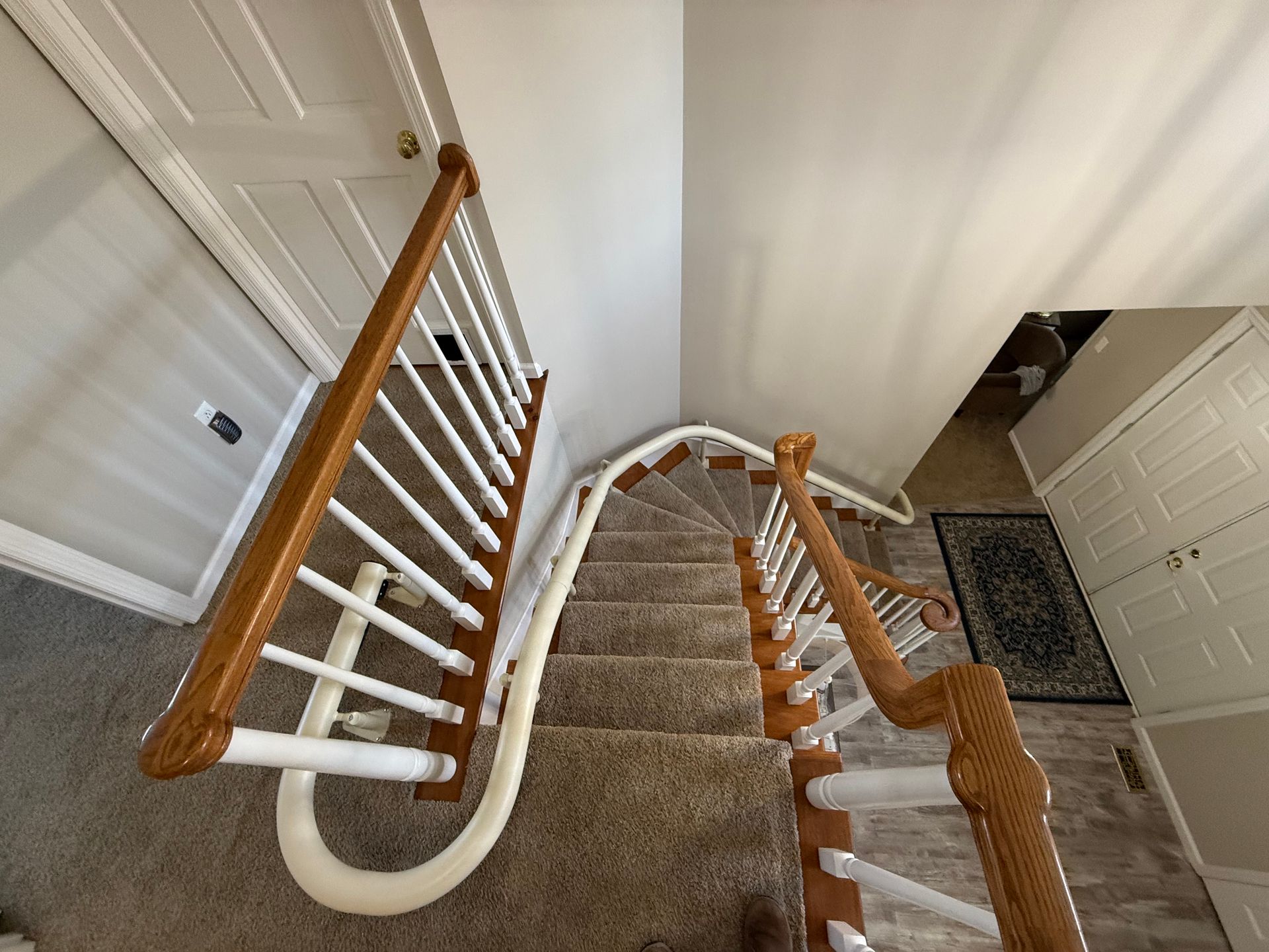 A curved staircase with a wooden railing and a white railing