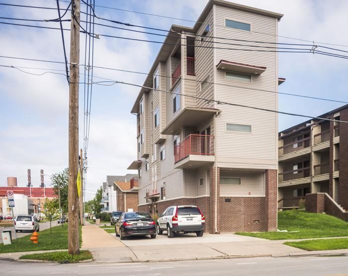Modern apartment building with balconies, parked cars, and power lines.