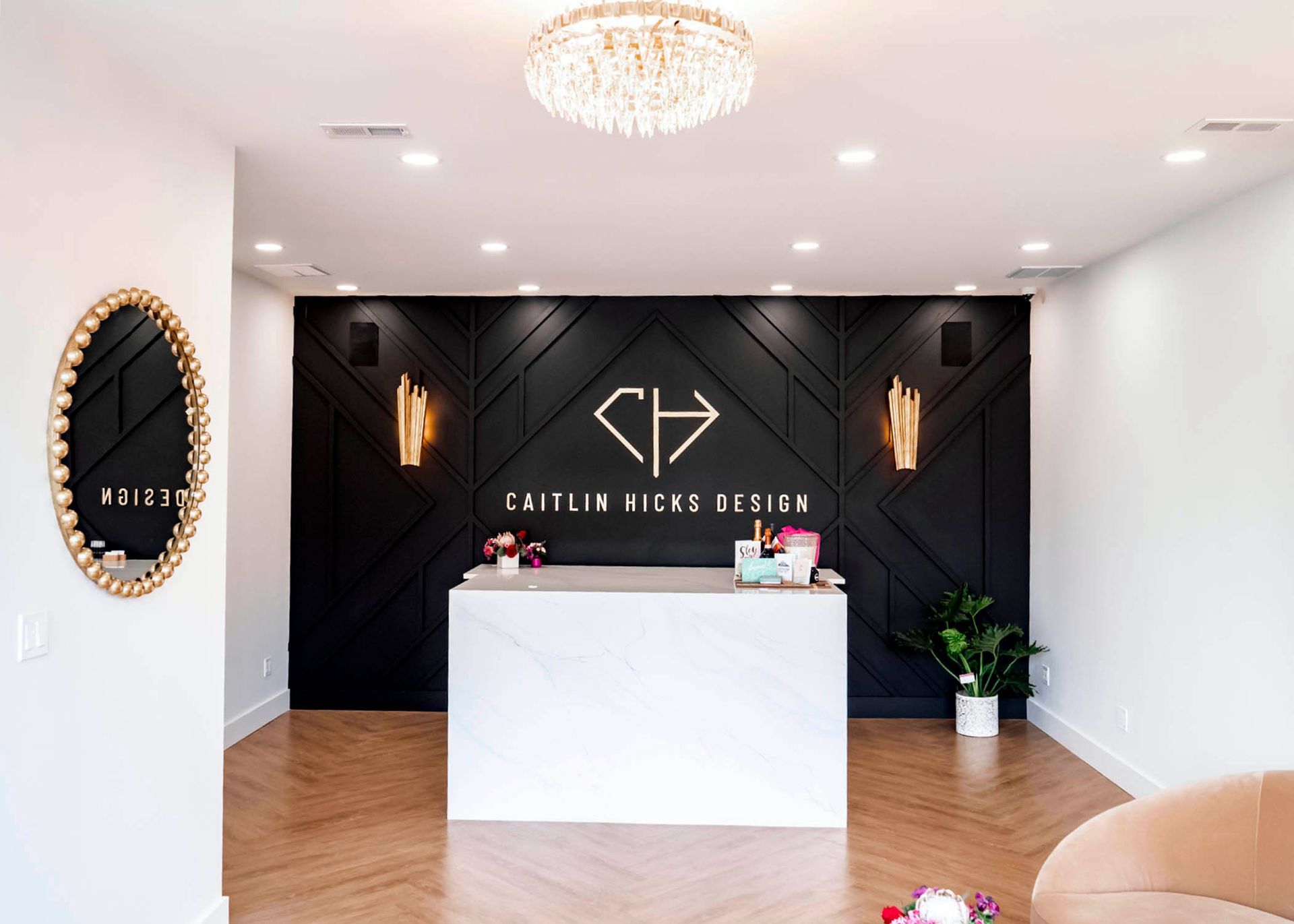 Modern office reception area with black accent wall, white counter, and gold accents.
