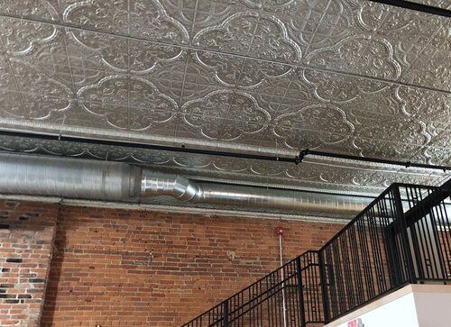 Brick wall, metal ceiling, and black staircase in an industrial space.