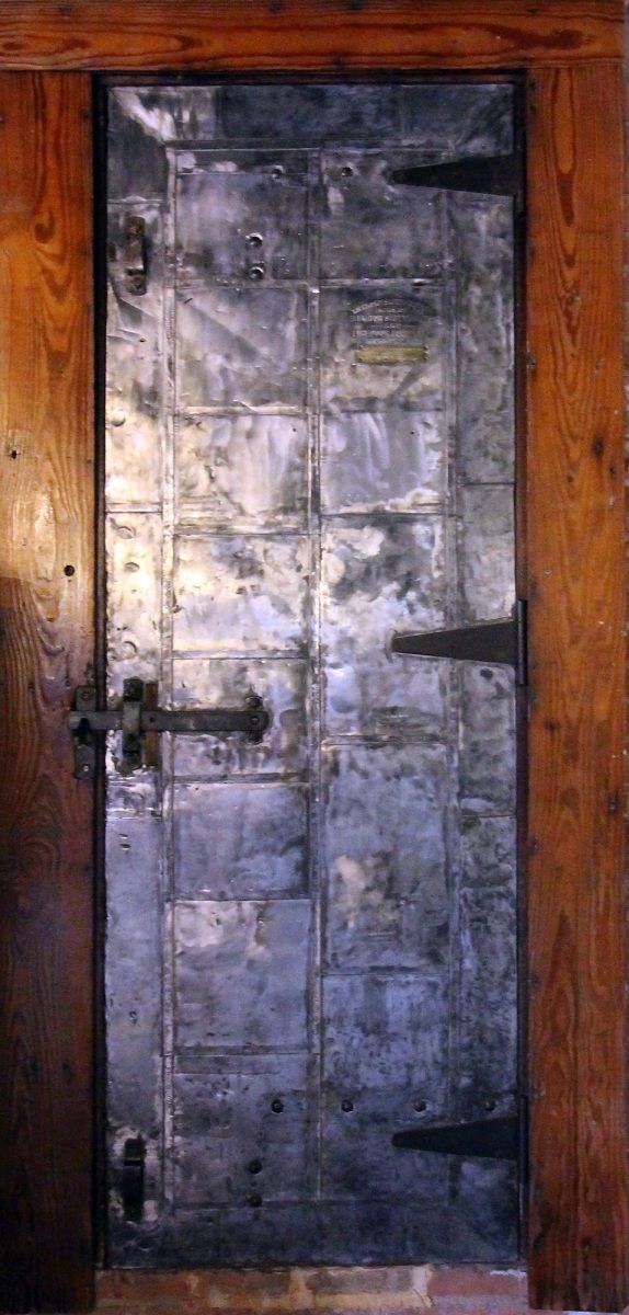 Metal-plated door set within a wooden frame, featuring a latch and hinges.