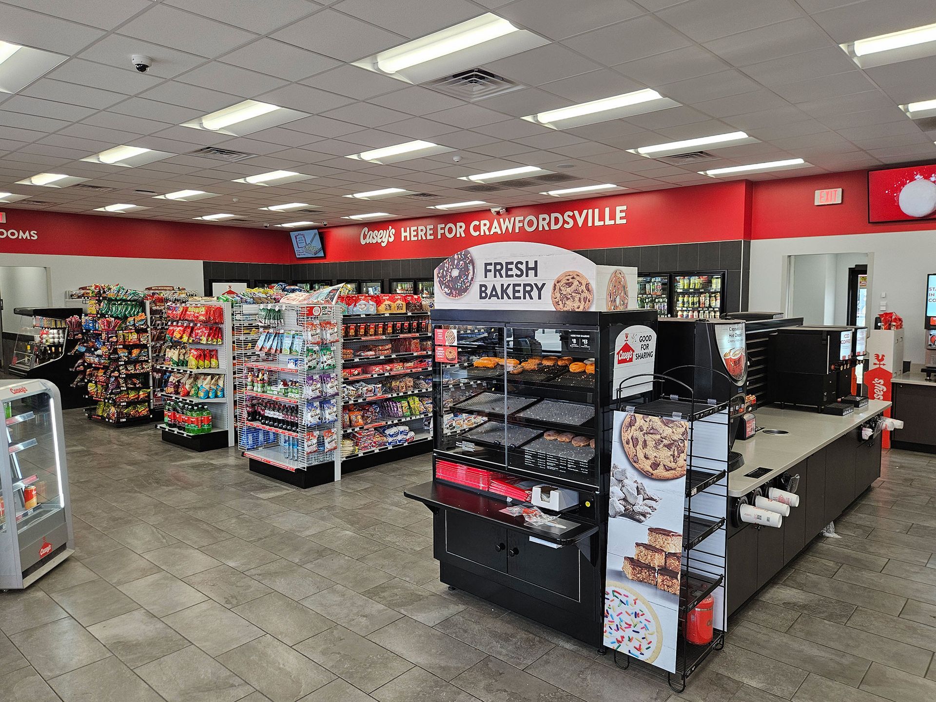 Interior of a convenience store, featuring shelves stocked with snacks, a bakery display, and a counter.