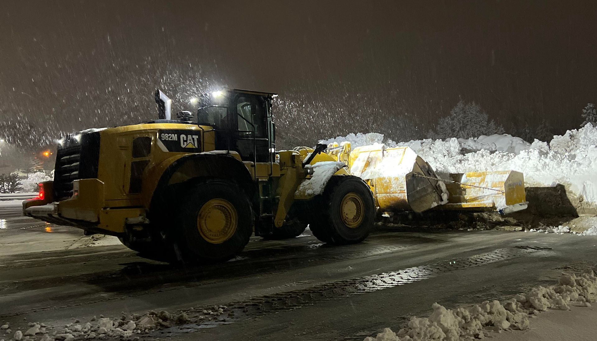 a bulldozer is clearing snow from a parking lot at night
