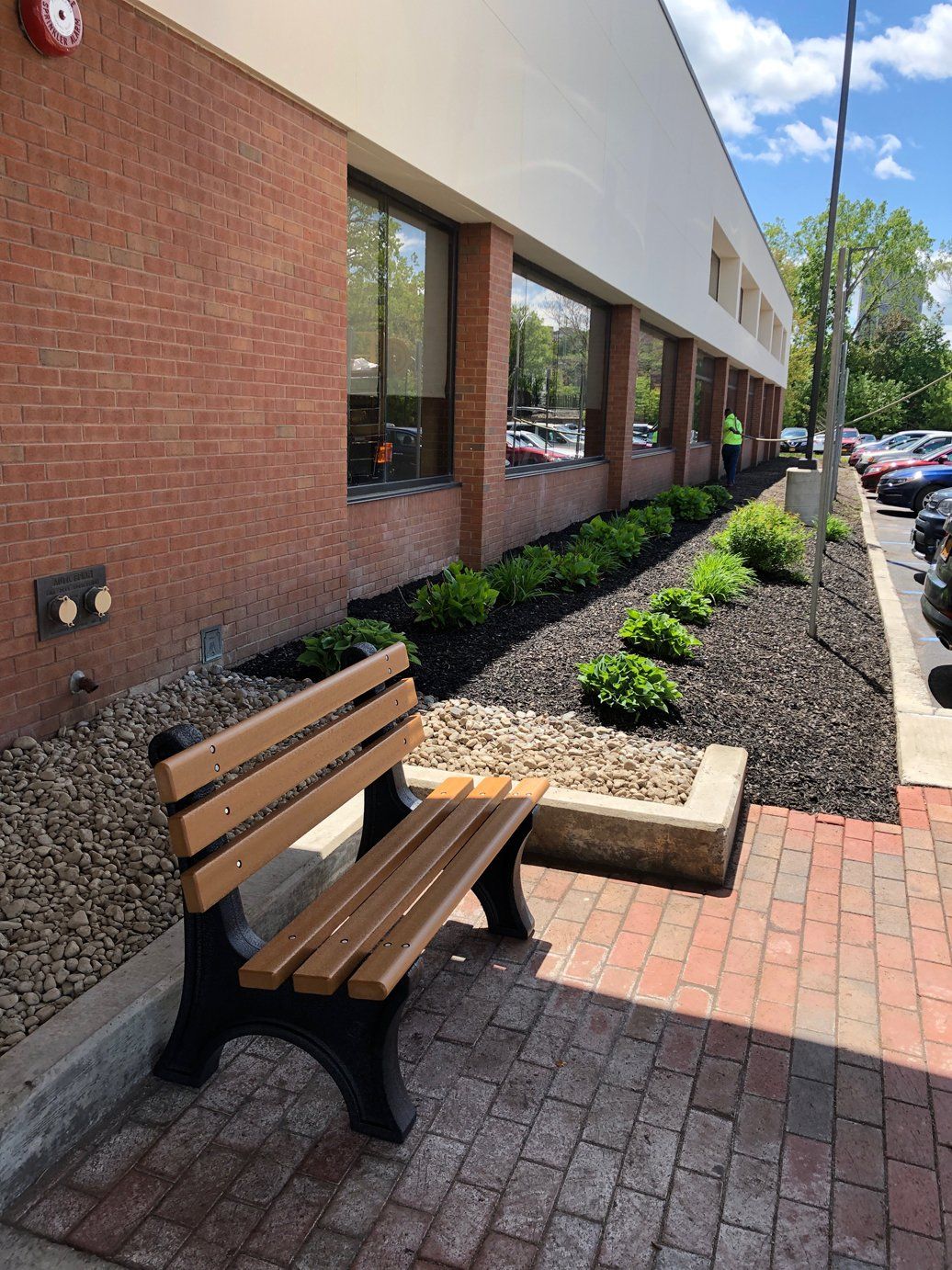 a wooden bench  with landscaping in front of a brick building