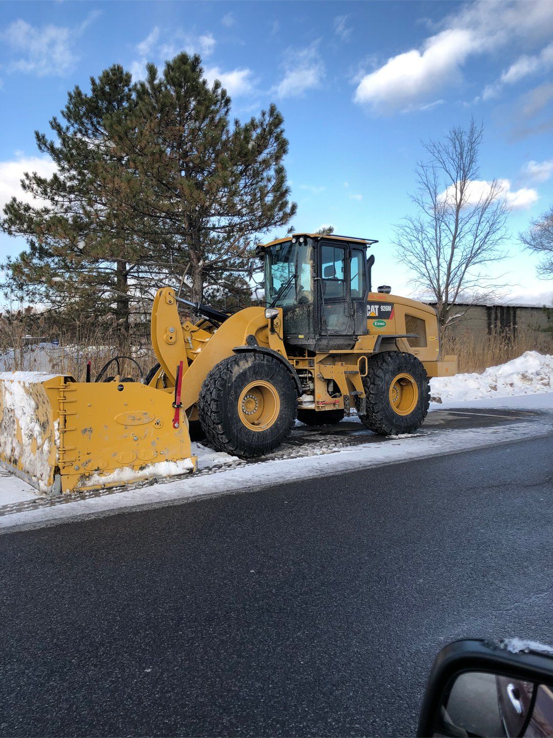 a yellow bulldozer is moving snow in a parking area .