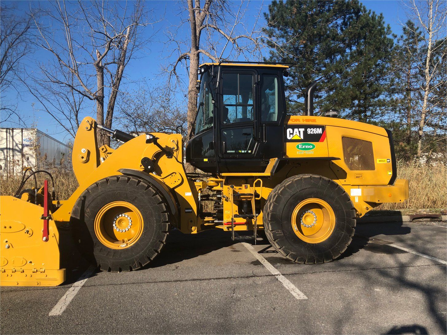 a yellow cat wheel loader is parked in a parking lot .