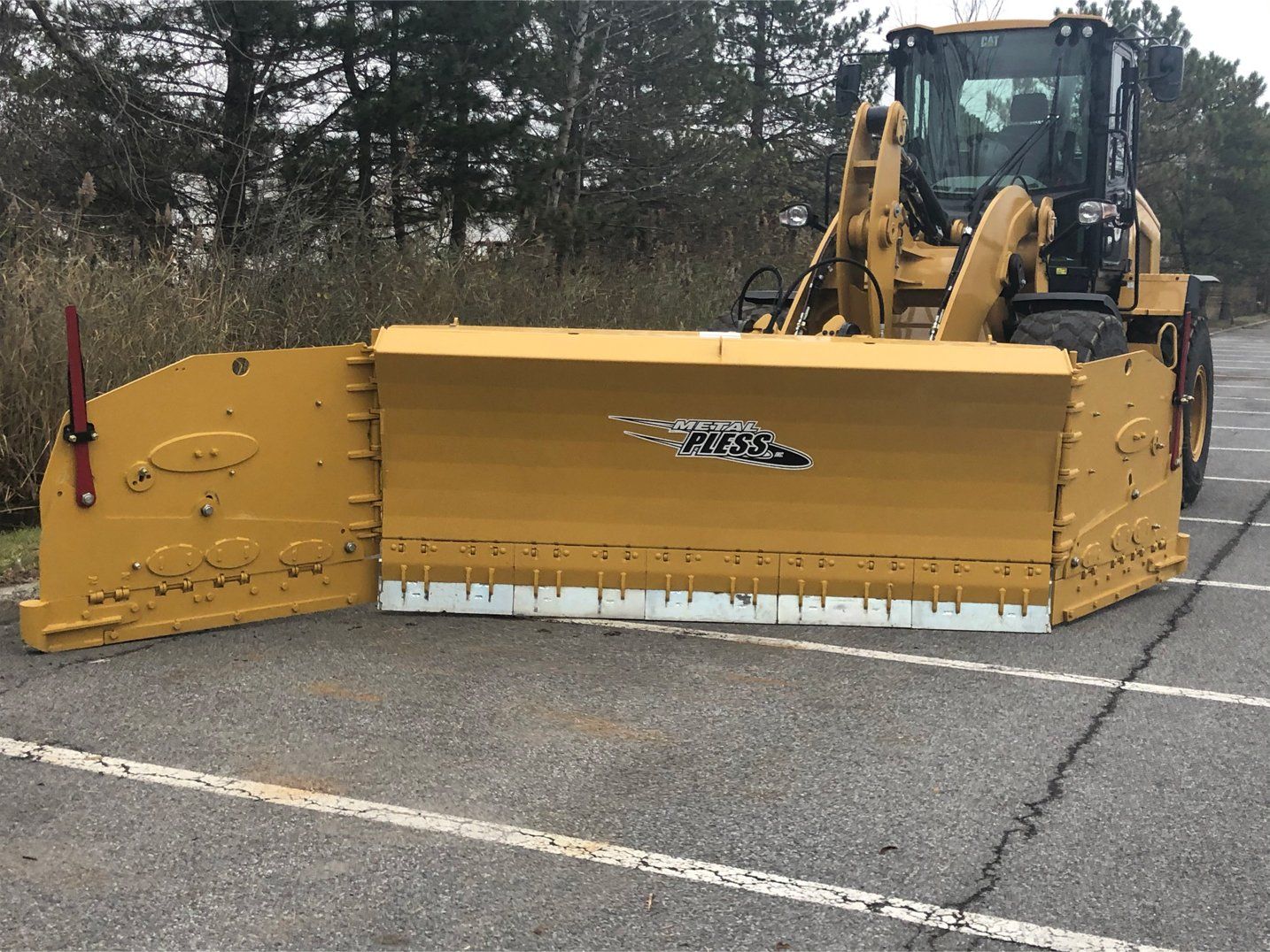 a yellow snow plow is parked in a parking lot .