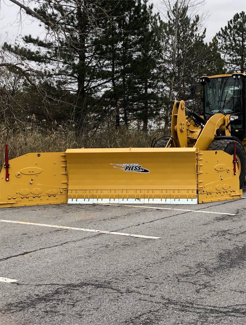 a yellow snow plow is parked in a parking lot .