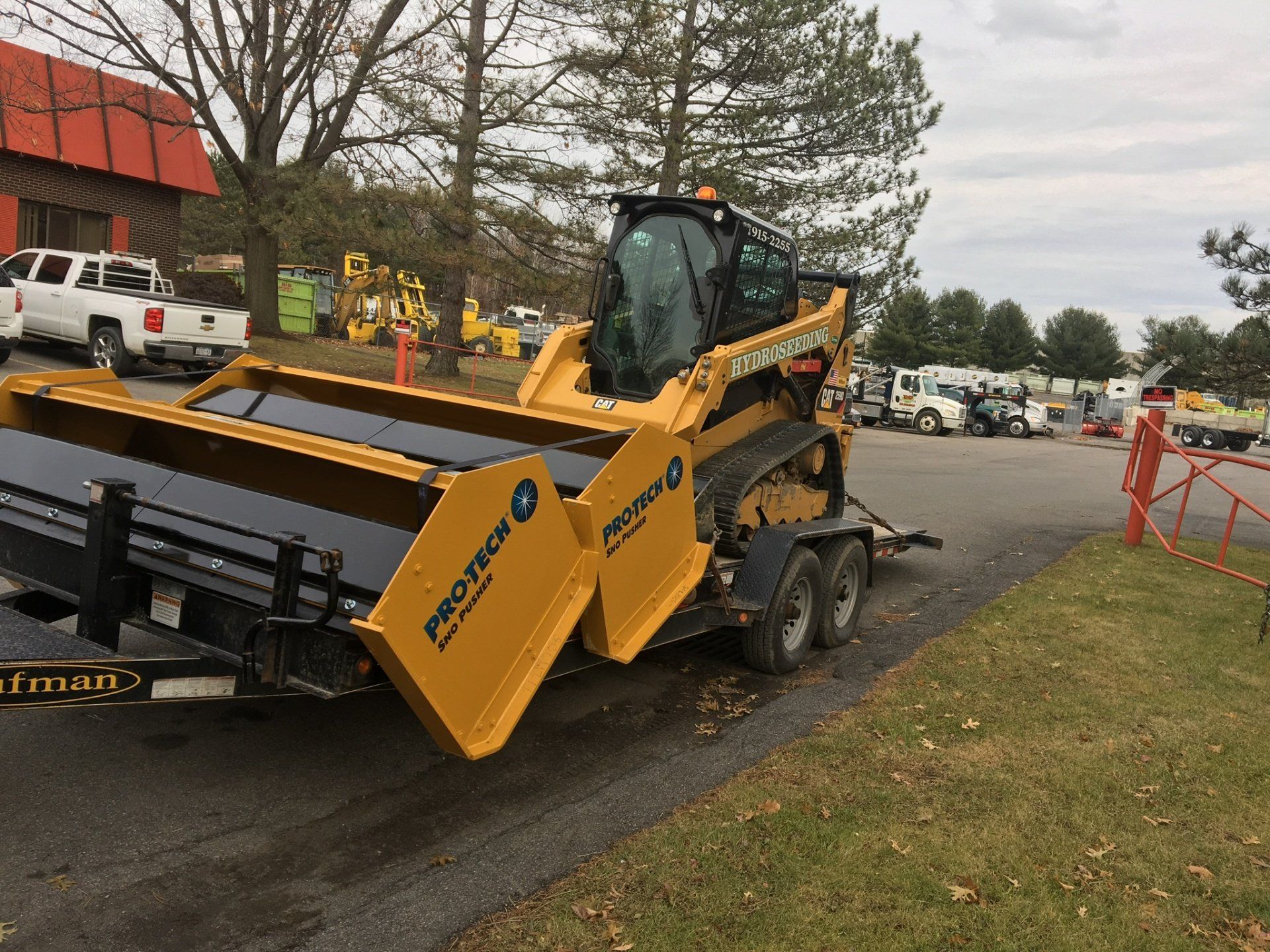 a yellow tractor is on a trailer in a parking lot .