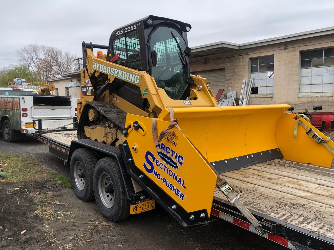 a yellow tractor is sitting on top of a trailer .