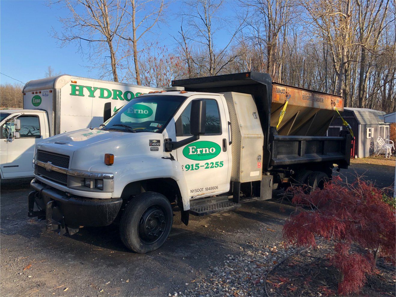 a white dump truck is parked next to a white truck .