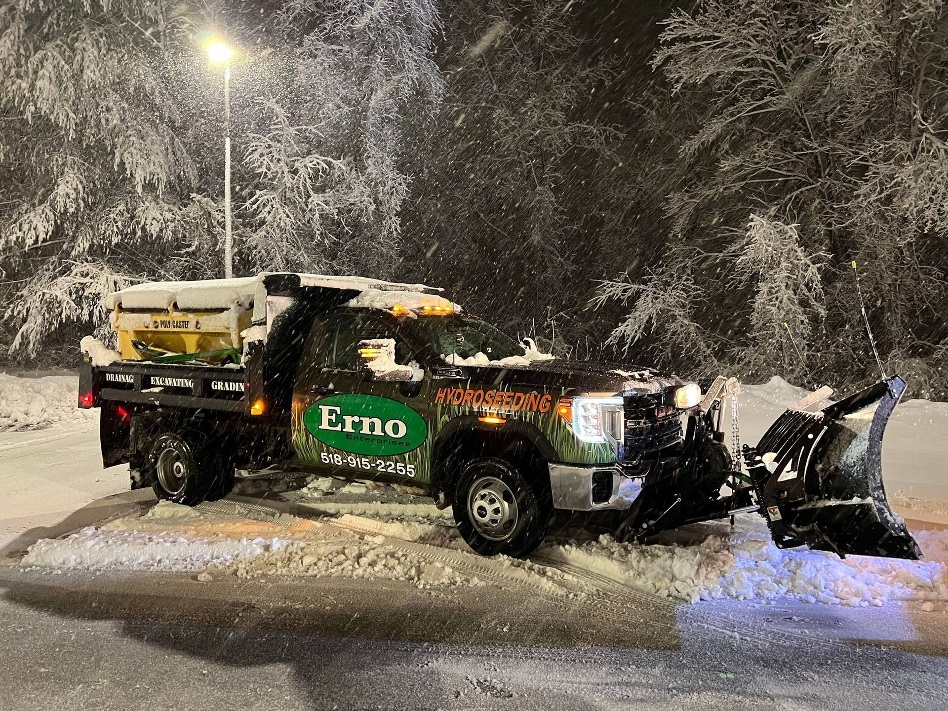 a truck with a snow plow attached to it is parked in the snow .