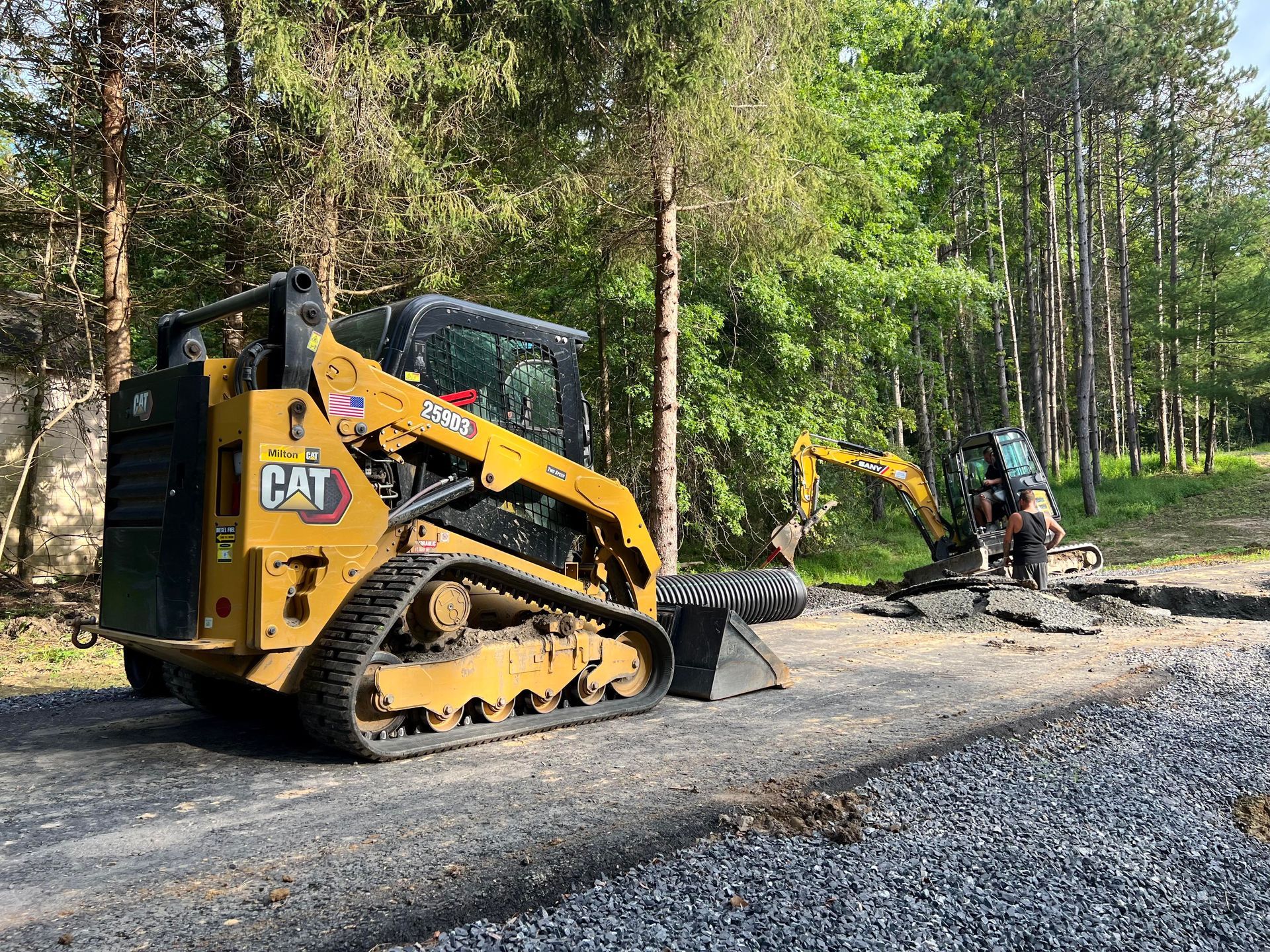 a yellow cat bulldozer is parked on the side of a road next to a yellow excavator .