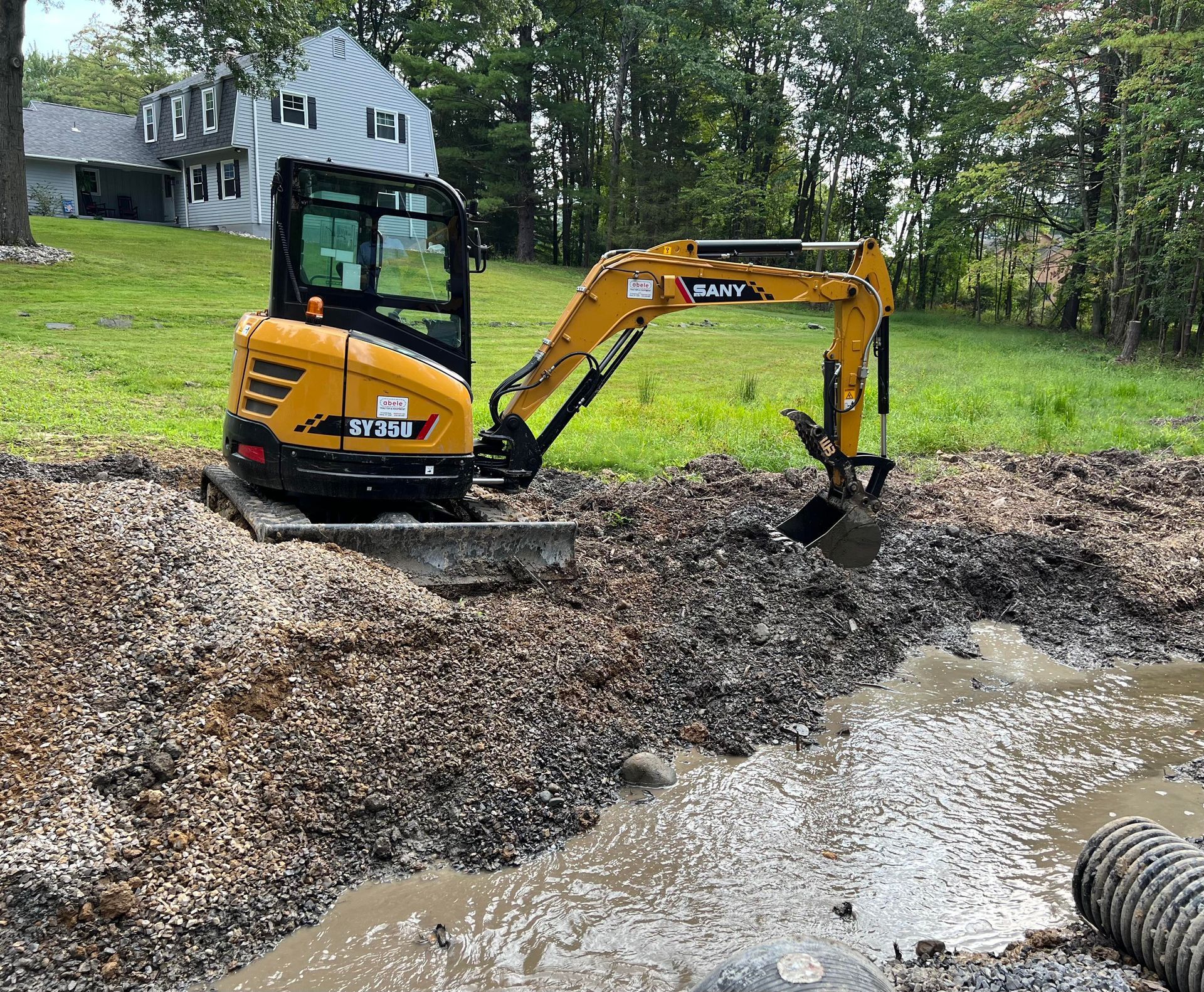 a small yellow excavator is digging a trench .