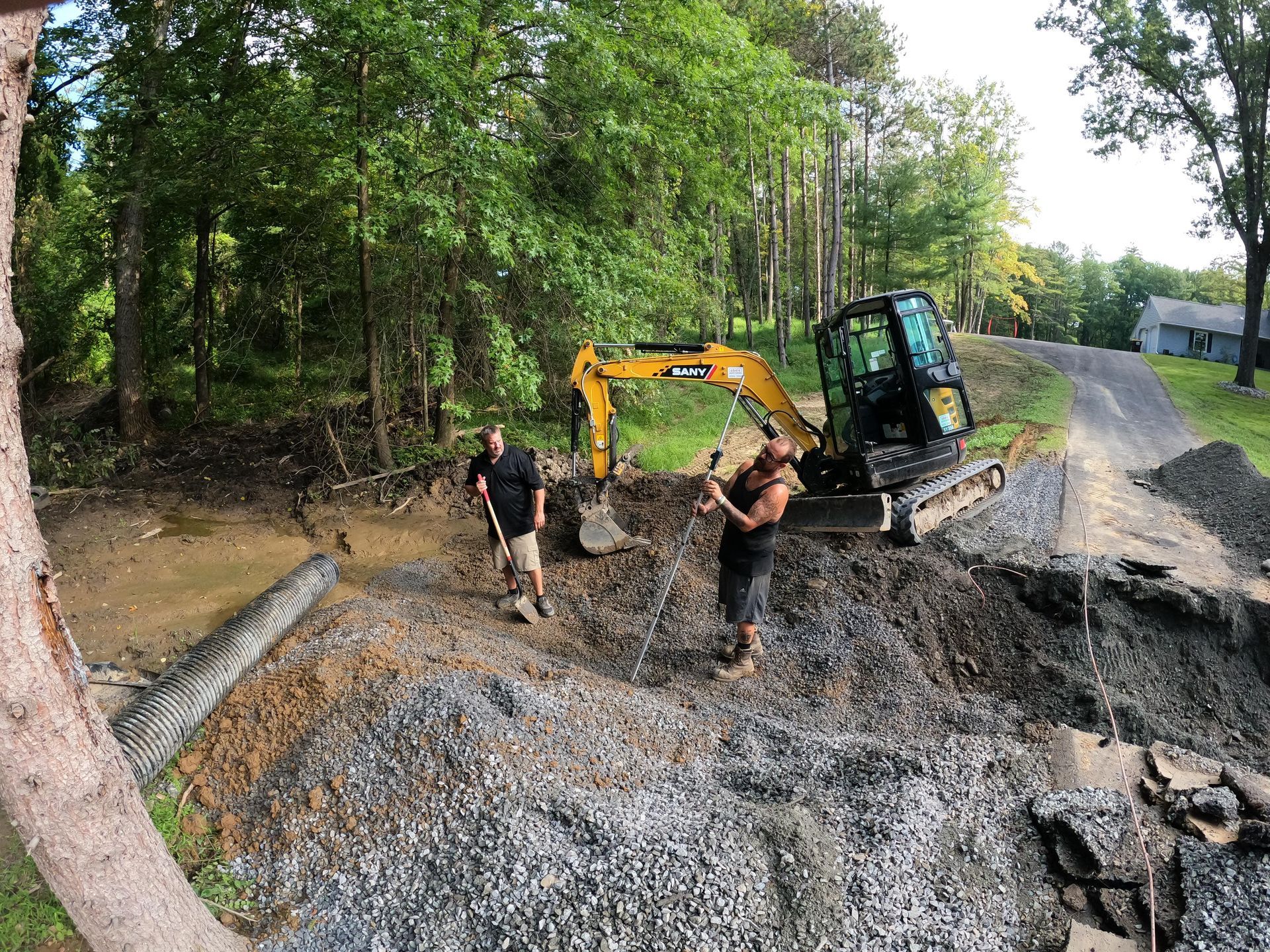 Workers standing next to a bulldozer digging a hole.