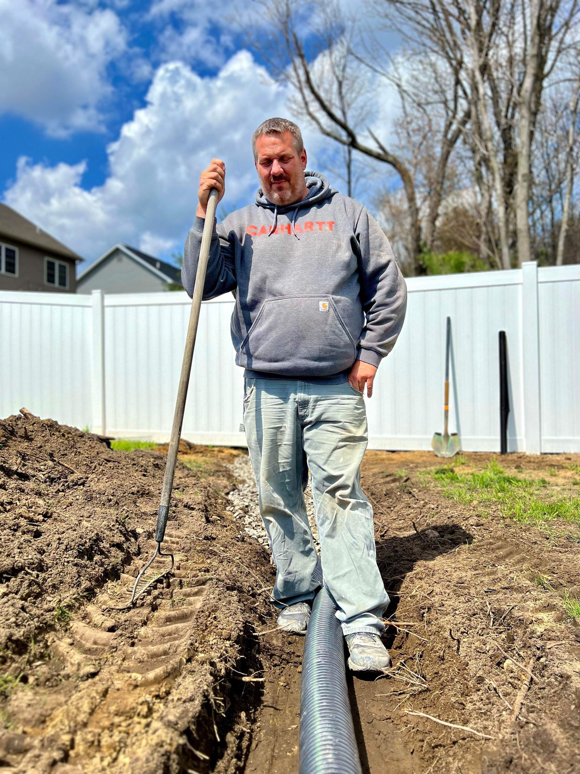 a worker is standing in a dirt field holding a shovel .