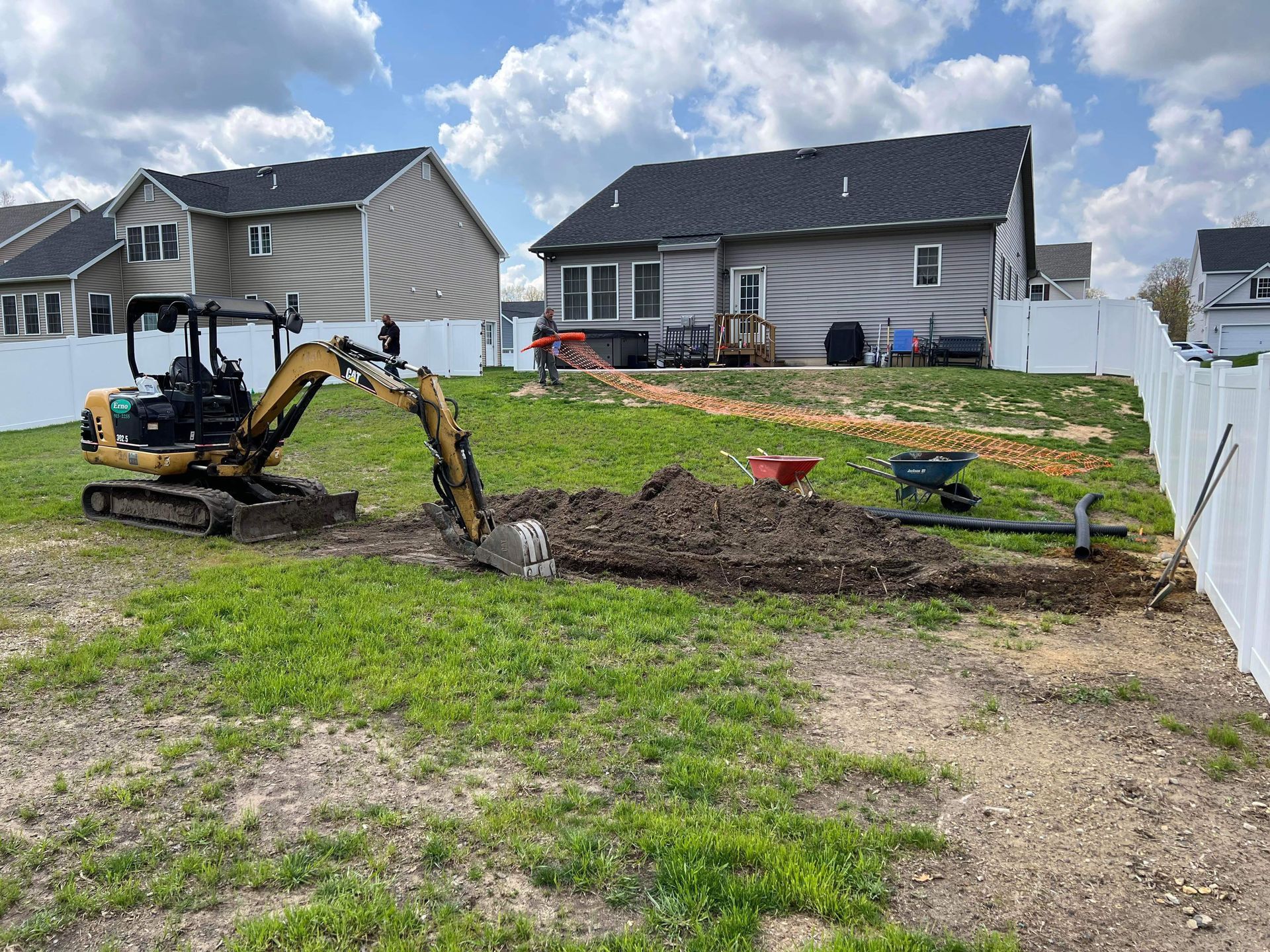 a small excavator is digging a hole in a yard in front of a house .