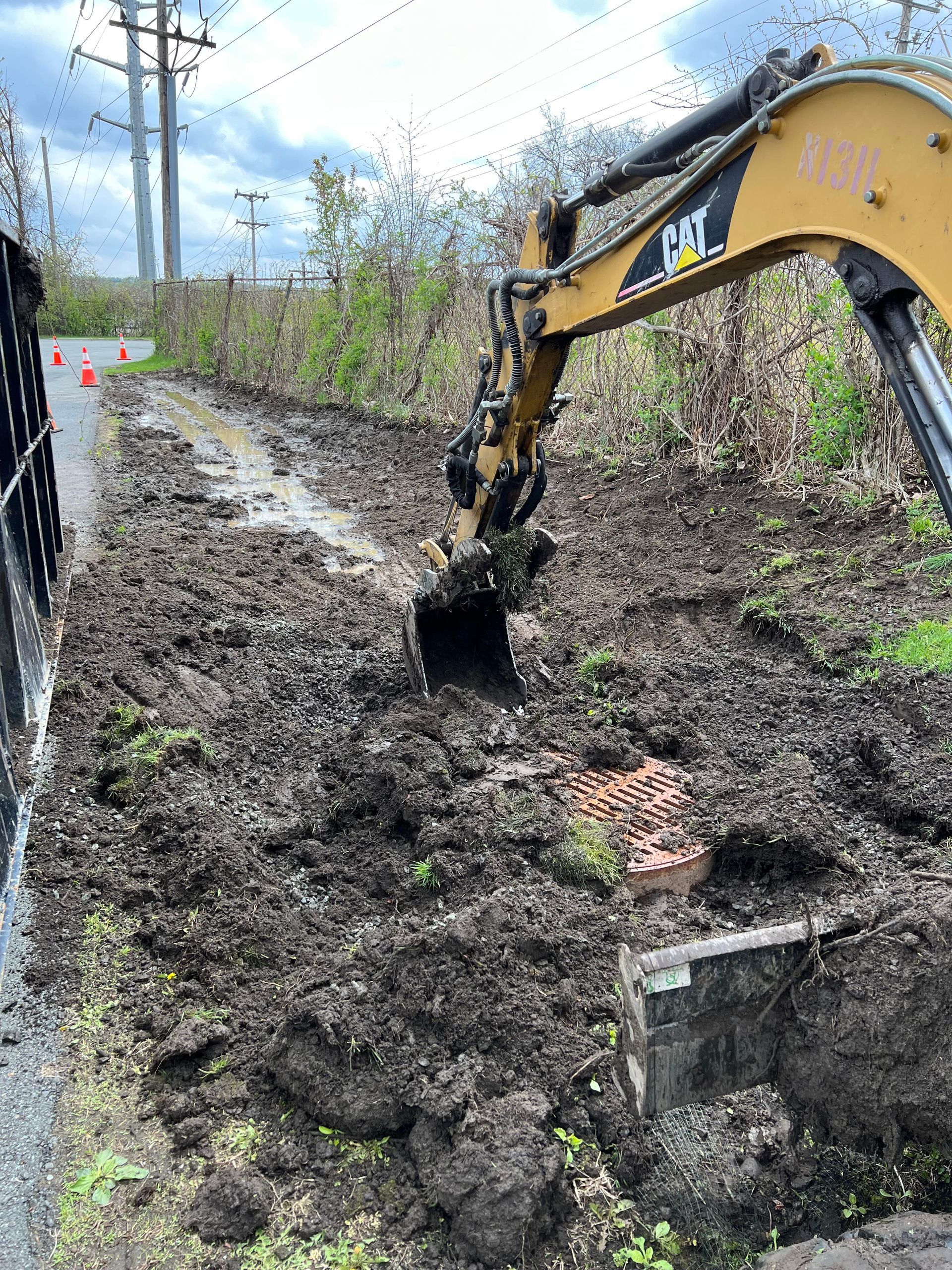 a cat excavator is digging a hole in the dirt next to a road .