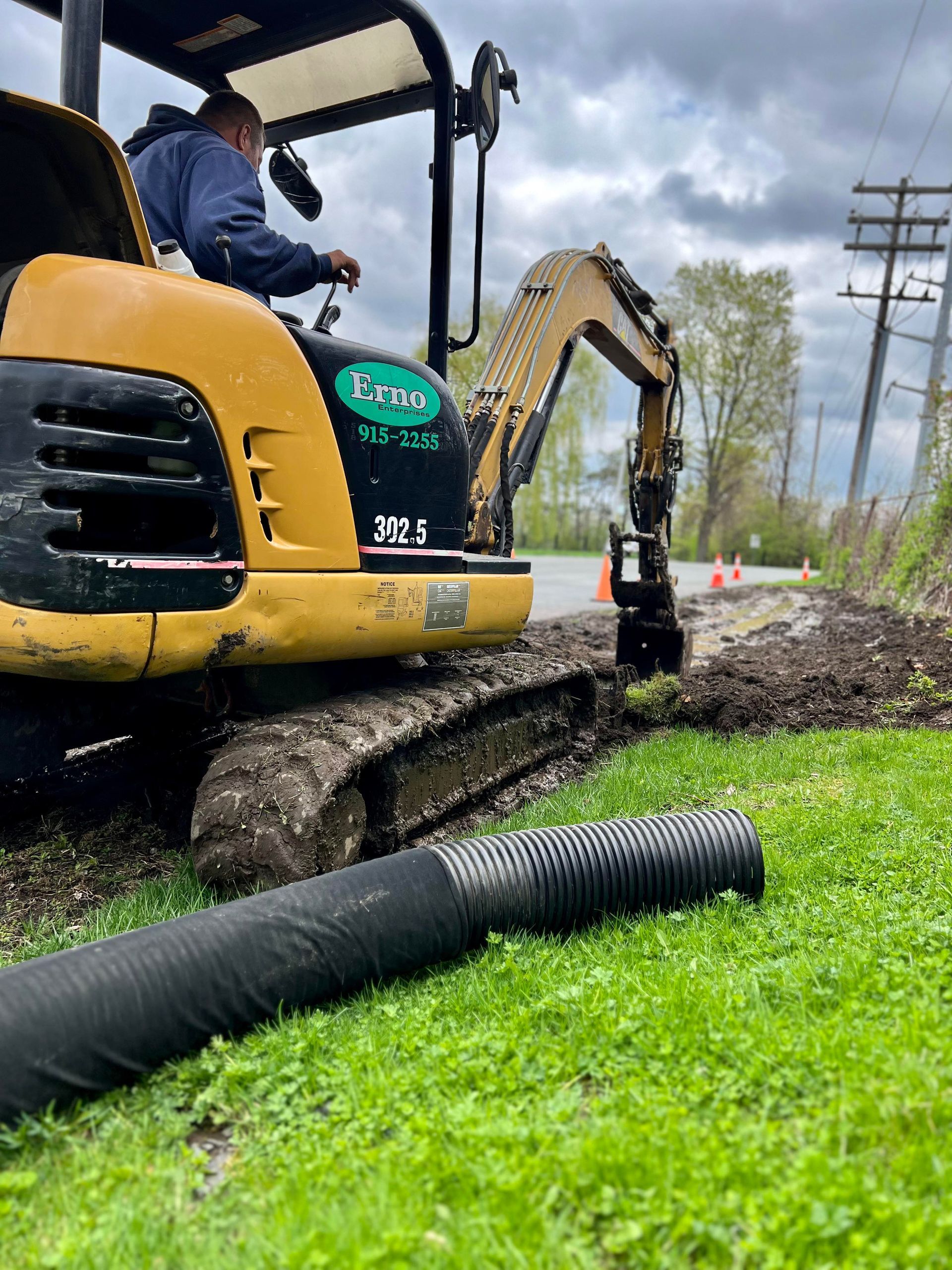 a man is operating a small excavator on a grassy field .