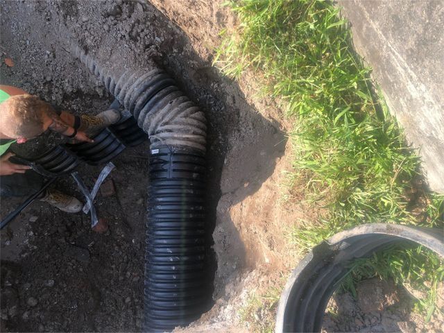 a man is working on a drain pipe in the dirt .